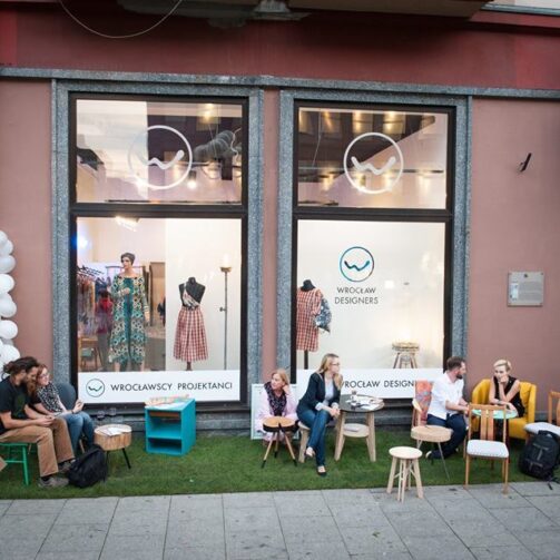 Wrocławska ulica: przed sklepem Wrocławscy Projektanci, przy stolikach siedzą młodzi, rozmawiający ze sobą ludzie