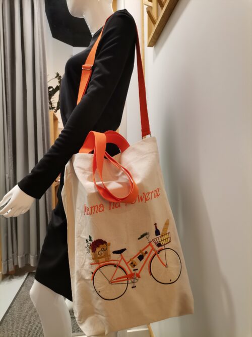 Torba Mama na rowerze z wyhaftowanym rowerem i napisem, prezentowana w przymierzalni na ramieniu manekina