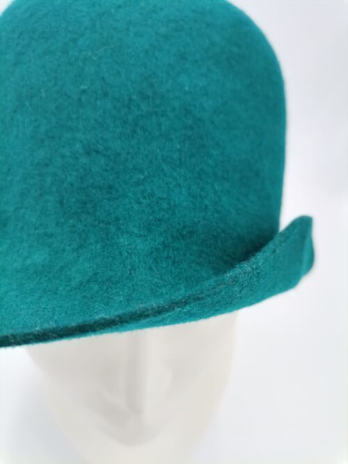 Zielony kapelusz prezentowany na głowie manekina - zbliżenie.