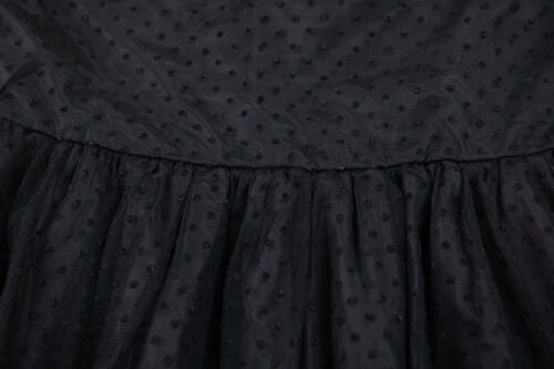 Tiulowy, siatkowy materiał czarnej sukienki w małe czarne groszki